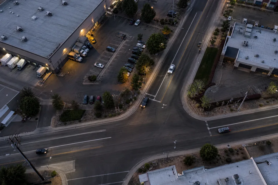 Aerial view straight down on a commercial district with warehouse rooftops, parking lot and loading docks at dusk
